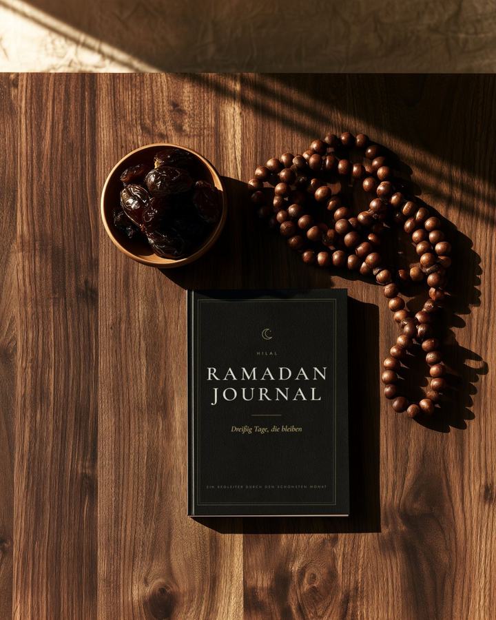 Das Ramadan Journal als Taschenbuch auf einem Holztisch, daneben Datteln und eine Gebetskette.